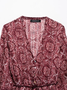 Détail de robe rouge foncé à col en V avec boutons blancs et ceinture assortie à la taille