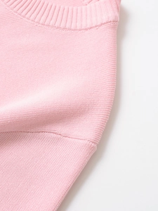 Detailed close-up of pink knit dress collar and sleeve seams with fine ribbing detail