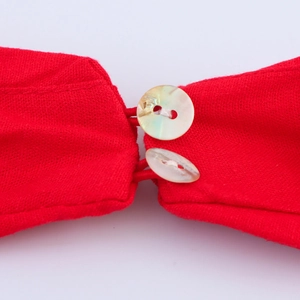 Détail du tissu en maille rouge avec deux boutons en nacre irisés et attaches à boucles