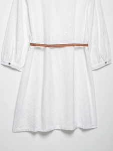 Détail de la robe blanche à manches longues avec broderie anglaise et ceinture fine