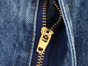 Vue détaillée de la fermeture éclair métallique et des coutures jaunes sur denim bleu