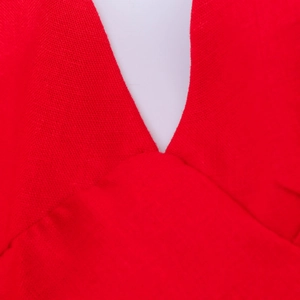 Gros plan du décolleté en V profond sur robe d'été rouge montrant le tissu tissé