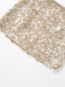 Detailed close-up of champagne sequins and fine stitching on the mini skirt hemline