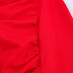 Vue macro des détails plissés et du tissu sergé résistant sur une robe d'été rouge