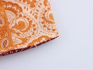 Macro detail of Bohemian paisley print fabric with high-quality orange and cream stitching