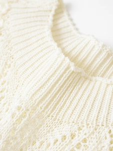Detailed macro view of the cream lace stitching and hollow out knit texture of the top