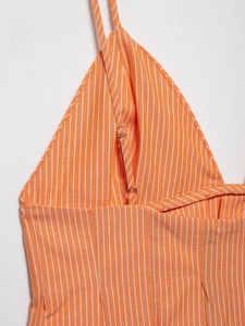Detail view of orange vertical striped fabric with thin strap and metal adjuster buckle