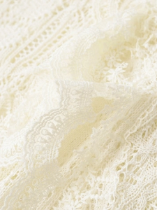 Detailed macro view of cream lace fabric with intricate floral patterns and hollow textures