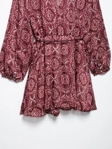 Détail d'une robe d'été à fleurs avec poignets boutonnés et une ceinture bordeaux fine