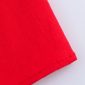Macro d'un tissu de robe rouge montrant la texture détaillée et la couture de précision