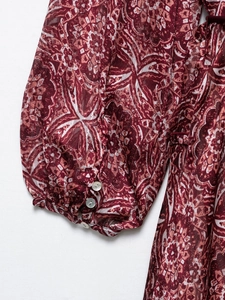Détail de la manche en mousseline bordeaux avec boutons en perle sur le poignet
