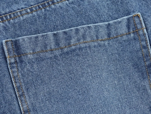 Gros plan sur le denim bleu délavé avec des surpiqûres jaunes détaillées sur la poche arrière