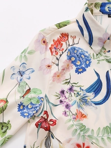 Detailed close-up of floral print and satin texture on a white long sleeve shirt