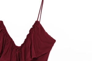 Detailed view of dark red ruffled V-neckline with thin straps and raw edge detailing