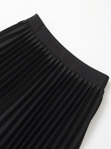 Detailed macro view of sharp knife-pleats and matte texture on high waist black skirt