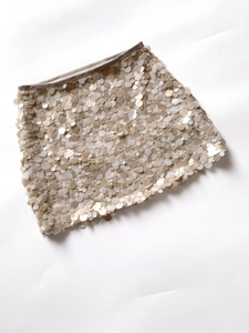 Detail shot of overlapping champagne gold sequins on a stylish mini skirt surface