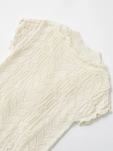 Close-up of cream lace knit top showing intricate hollow crochet and wave textures