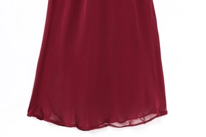 Detailed close-up of dark red dress hemline showing light fabric texture and rolled edges