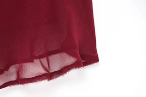 Close-up of deep red chiffon fabric with micro-pleated texture and raw hem detailing