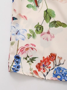 Detailed close-up of floral and bird print on elegant cream satin fabric texture