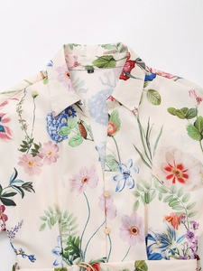 Detail of floral print chiffon shirt featuring golden buttons and waist belt design