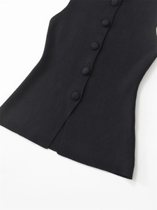 Detail of black knit top featuring matching fabric buttons and a stylish side slit hem