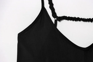 Dettaglio del top nero con spalline elastiche arricciate e cursori di regolazione in metallo