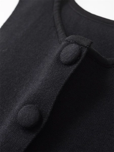 Close-up of soft black knit top featuring matching fabric-covered buttons and rib neckline