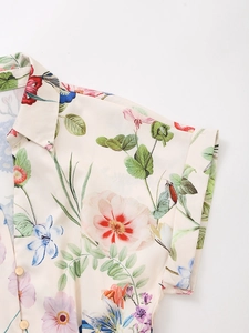 Detail of floral print silk blouse with cuffed short sleeves and gold metal buttons