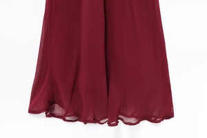 Detailed view of burgundy chiffon dress with ruffled hemline and delicate wavy edges