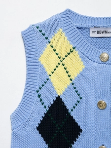 Close-up of diamond pattern knit vest with ornate gold metal buttons on light blue fabric