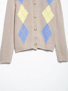 Detail of beige knit cardigan with argyle pattern and vintage gold buttons for spring