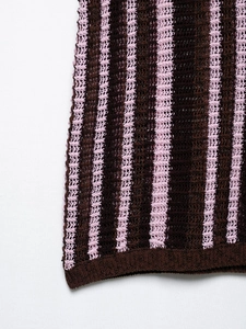 Detailed macro view of the brown and pink striped hollow knit fabric and ribbed hem finish