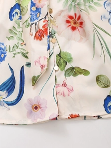 Detailed macro view of silk texture floral dress with golden buttons and waist tie