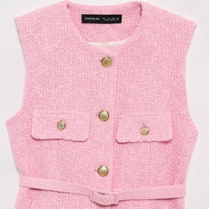 Detail of pink tweed vest dress with gold embossed buttons and woven texture