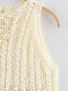 Detail of cable knit pattern with decorative faux pearls on a cream round neck top