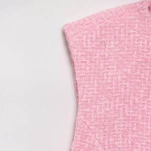 Detailed macro view of pink tweed fabric texture with intricate weaving patterns on vest