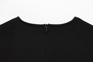 Detailed view of the round neckline and invisible back zipper on a black sleeveless dress