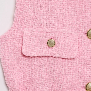 Detail of pink tweed fabric with textured weave and ornate gold metal buttons