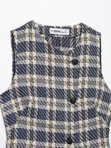 Détail à plat d'un gilet en tweed bleu avec étiquette blanche et boutons noirs