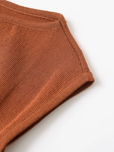 Close-up of caramel knit fabric showing fine texture and professional stitching details