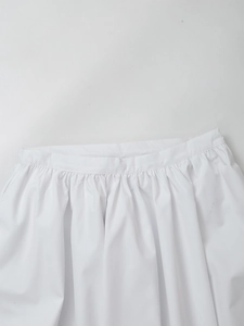 Detailed view of the elastic pleated high-waisted white skirt in smooth cotton fabric