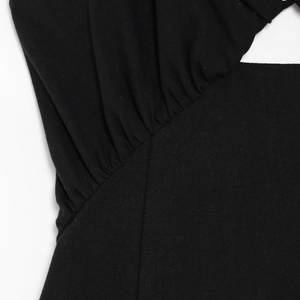 Detail of black irregular sleeveless dress featuring shirred fabric and cutout design