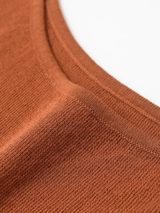 Detailed macro view of the textured brown knit fabric and rib-knit neckline stitching