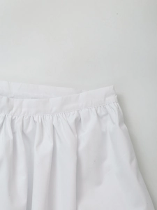 Close-up of white high-waisted pleated skirt featuring fine stitching and soft gathering