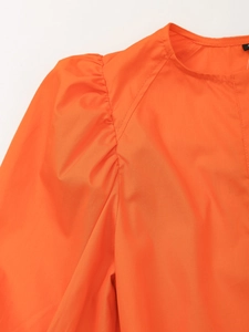 Détail des manches bouffantes et coutures de l'encolure sur cette robe d'été orange chic