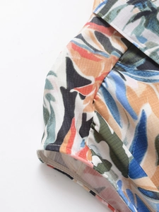 Gros plan sur l'imprimé floral tropical d'une robe à col en V avec motifs de feuilles