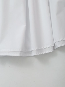 Detailed close-up of white pleated skirt hem featuring double-needle flat stitching detail
