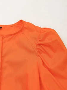 Gros plan du col rond et des manches bouffantes plissées d'une robe orange vif