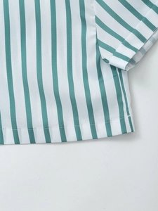 Détail d'une chemise en popeline rayée verte et blanche avec ourlets et texture du tissu